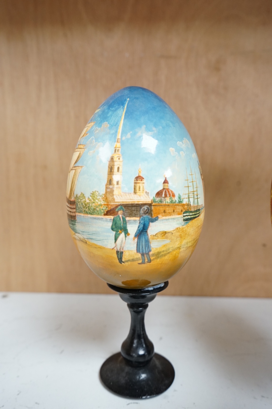 Five Russian painted and lacquered 'eggs' on stands, one inscribed in cyrillic, largest 21cm high